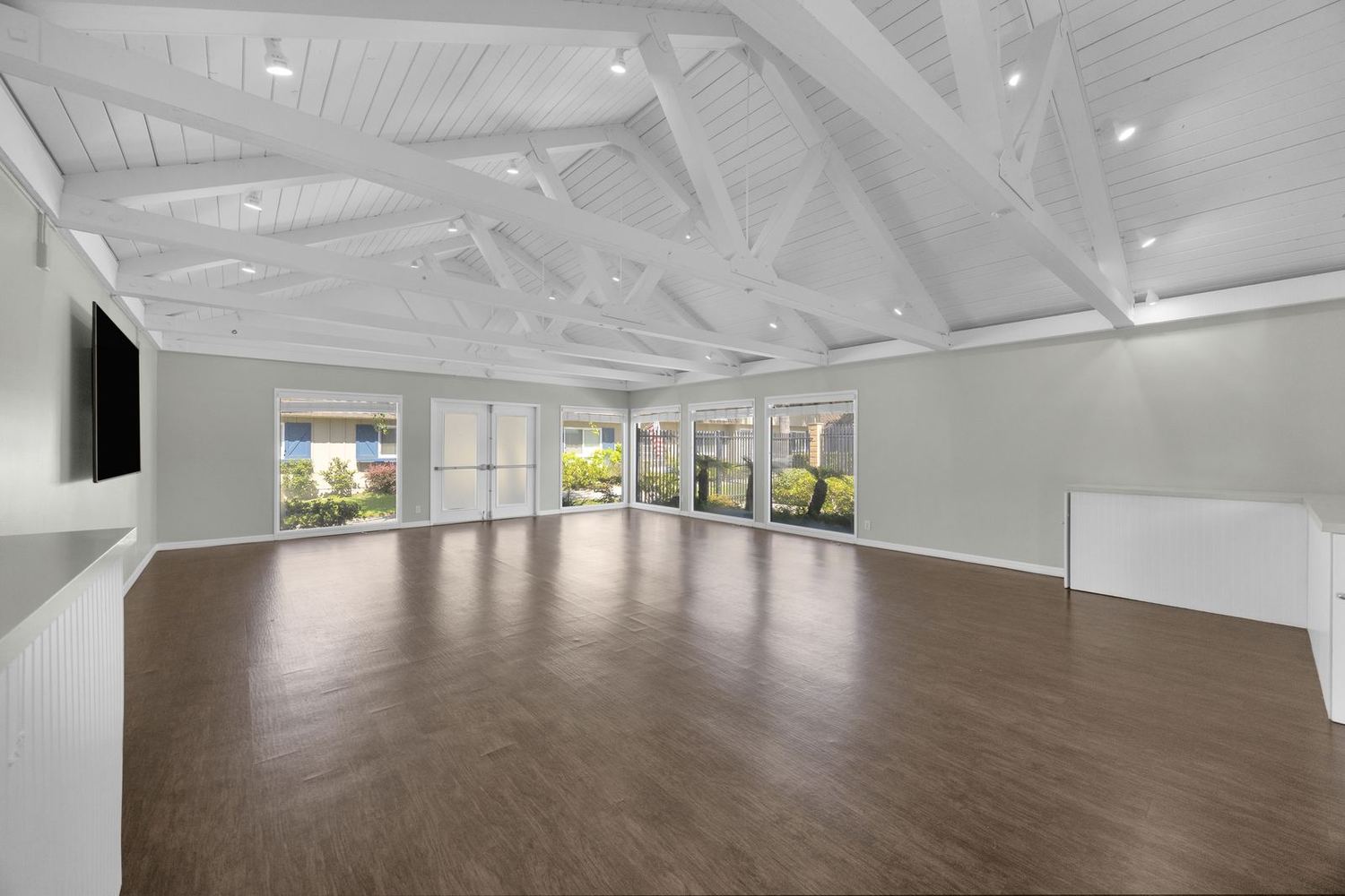 Inside the Clubhouse — open white trusses and a wall of windows onto the lawn